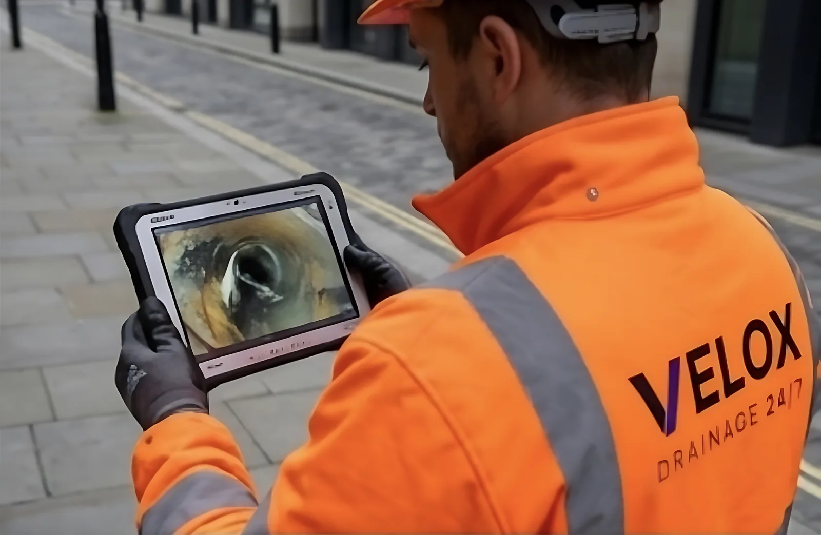 Velox drainage engineer viewing live CCTV footage from inside a drain on a rugged tablet